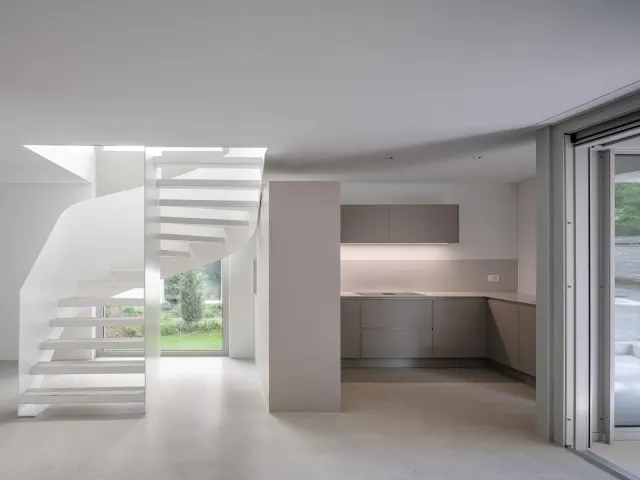 Heller Wohnraum mit weisser Treppe und Küche